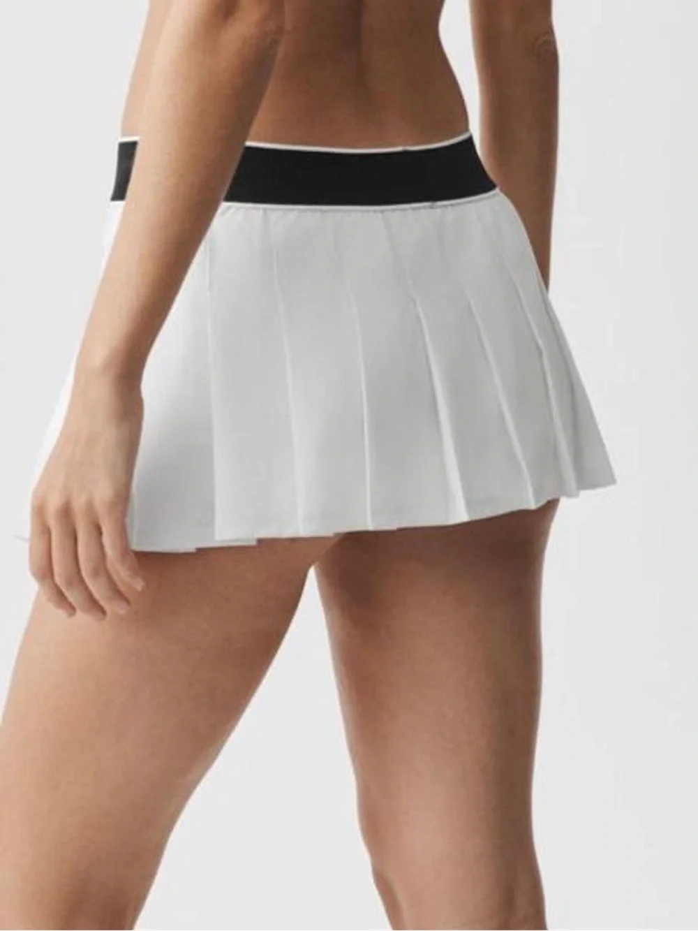 alo Yoga Low Rise AMP It Up Tennis Skirt in White with Black Waistband. SIZE: S